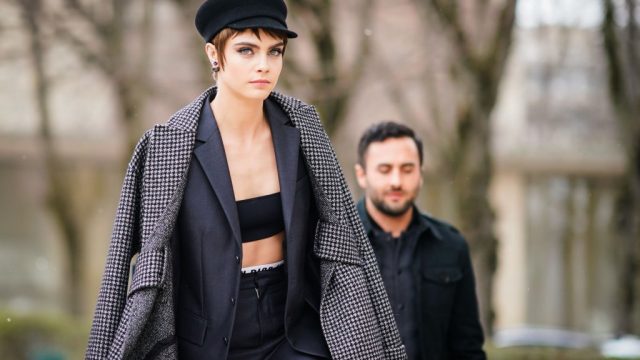 PARIS, FRANCE - FEBRUARY 27: Cara Delevingne wears a black cap, a gray blazer jacket, black bras, gray suit, outside Dior, during Paris Fashion Week Womenswear Fall/Winter 2018/2019, on February 27, 2018 in Paris, France.
