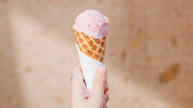 Cropped Image Of Person Holding Ice Cream Against Wall