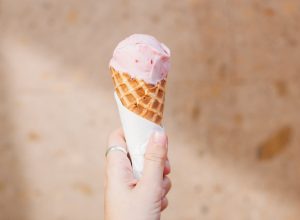 Cropped Image Of Person Holding Ice Cream Against Wall