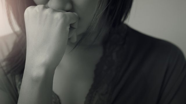 A woman with her fist at her mouth, displaying sadness