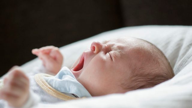 New Zealand doctor works while holding sleeping baby.