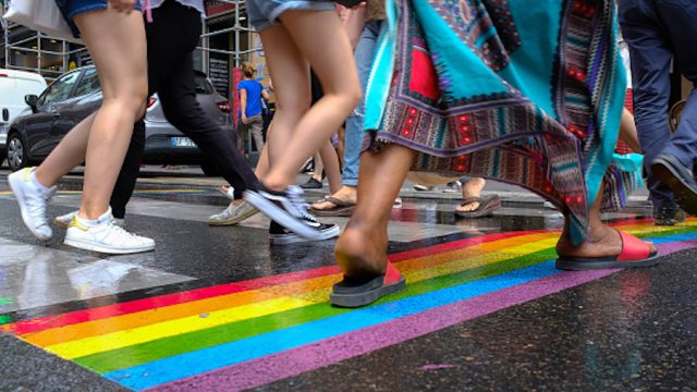 Pedestrians crossing the street at a Pride parade