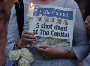 Woman holding up a newspaper at Capital Gazette shooting vigil