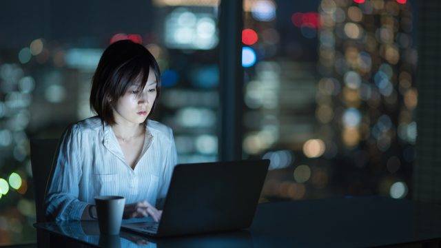 Businesswoman working late in office with city in background