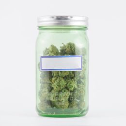 Detail of cannabis buds on green glass jar with blank label isolated on white - medical marijuana concept