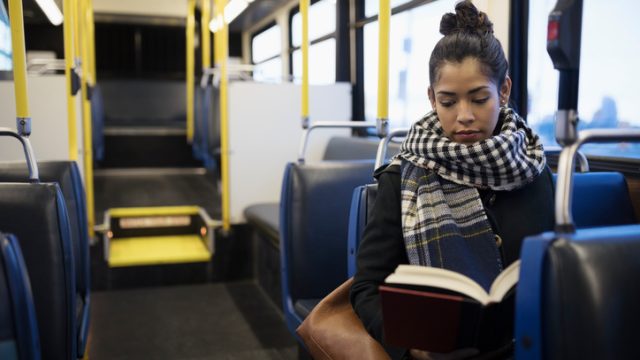 girl reading book on bus