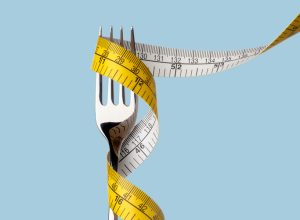 Fork with tape measure on blue background