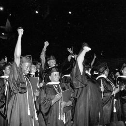 Black students giving the Black Power salute at a college graduation