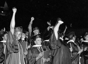Black students giving the Black Power salute at a college graduation