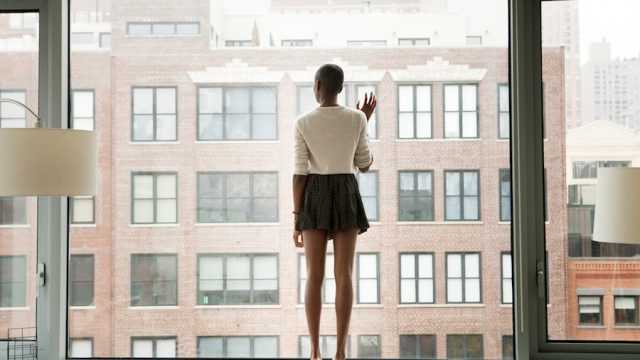 Woman looking out her window from apartment