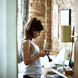 Woman in her 20s getting ready in the morning, laptop half open, reading text message