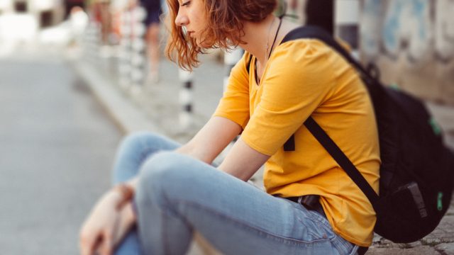 Moody teenage girl sitting on the street