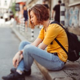 Moody teenage girl sitting on the street