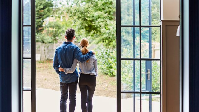 Married couple standing at window