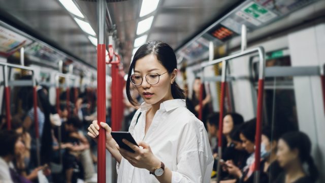 Young businesswoman looking at smartphone while riding on subway