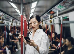 Young businesswoman looking at smartphone while riding on subway