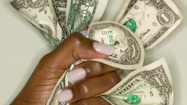 Woman's hand gripping dollar bills
