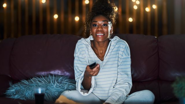 Woman binge-watching TV on her couch at night