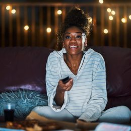 Woman binge-watching TV on her couch at night