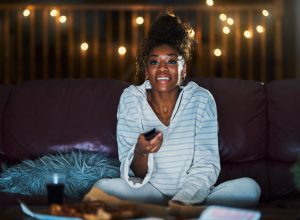 Woman binge-watching TV on her couch at night