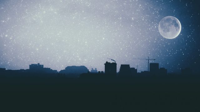 photo of full moon in sagittarius over city skyline