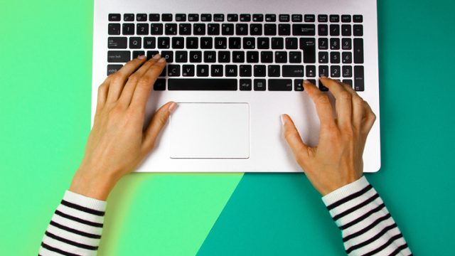 Woman's hands typing on a laptop