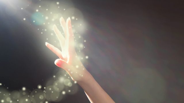 Woman's hand reaching towards glowing light