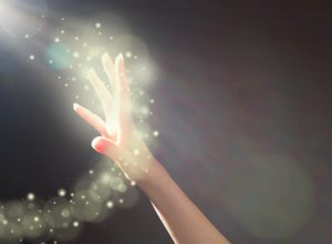 Woman's hand reaching towards glowing light