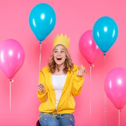 Woman celebrating with balloons and a party hat
