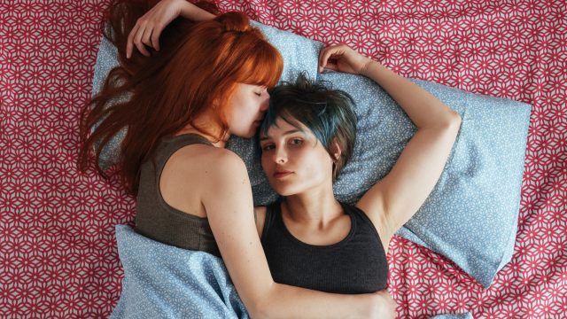 Portrait Of Lesbian Woman With Girlfriend Lying On Bed At Home