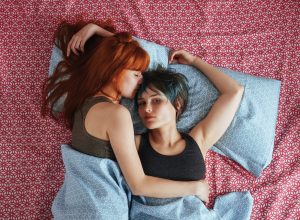 Portrait Of Lesbian Woman With Girlfriend Lying On Bed At Home