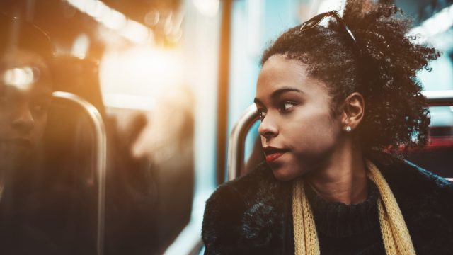 Girl riding the subway and looking at her reflection in the window
