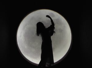 Woman's silhouette in front of full moon