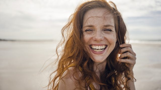 Portrait of a redheaded woman, laughing happily on the beach