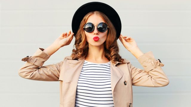 woman wearing summer to fall transitional pieces like a trench and hat