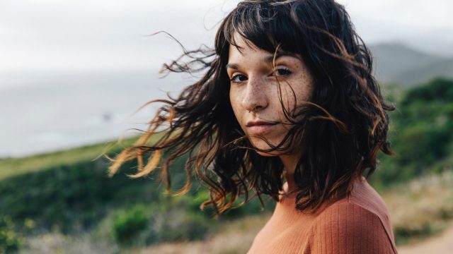 Portrait of confident woman with freckles standing against sky