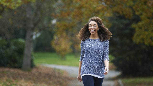Woman walking through city park and smiling
