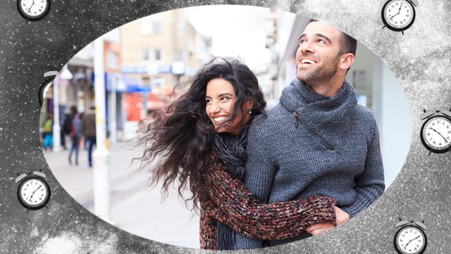 Woman smiling and hugging man on the sidewalk during fall