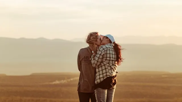 couple kissing in the middle of a field