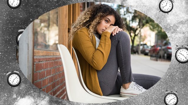 Pensive woman sitting on a white chair on a city sidewalk