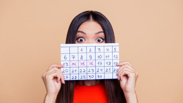 woman holding up calendar period came early