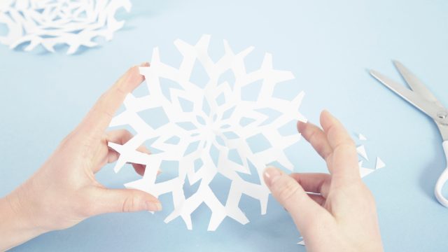 DIY snowflake luminaries, Woman making paper snowflakes, close-up of hands