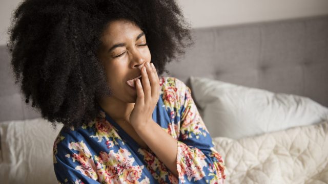 signs of sleep deprivation, woman yawning in bed