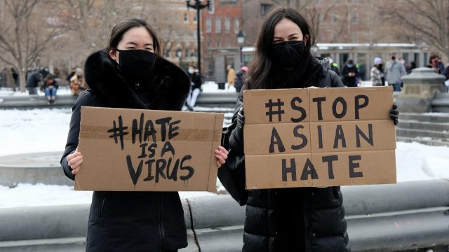 Two women holding signs that say stop Asian hate