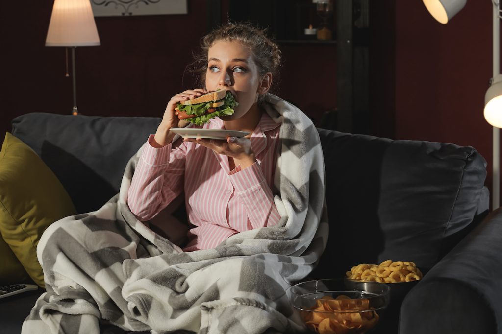woman eating sandwich couch blanket