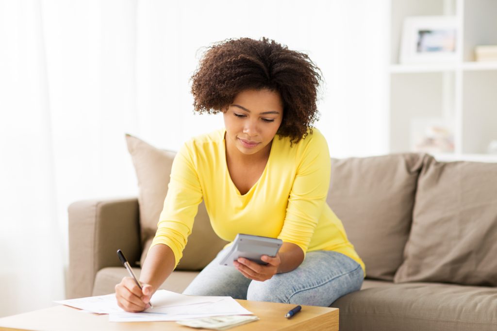woman on couch writing budgeting