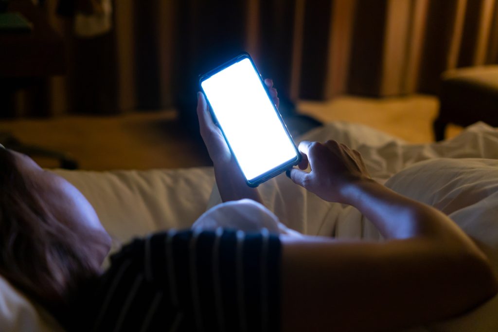 woman using phone on couch at night