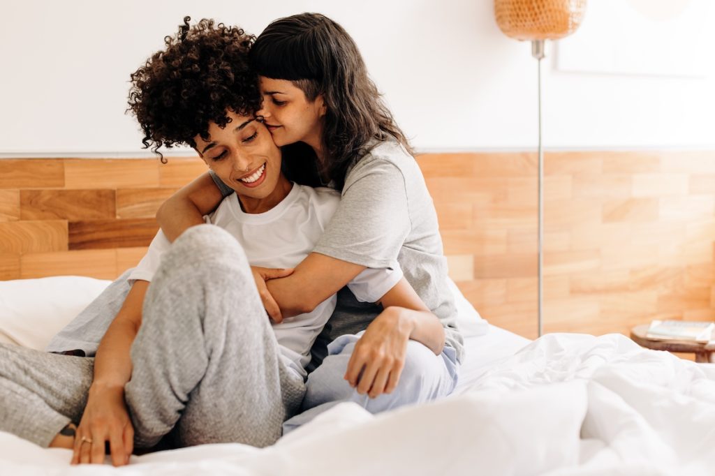 couple women dating in bed hugging