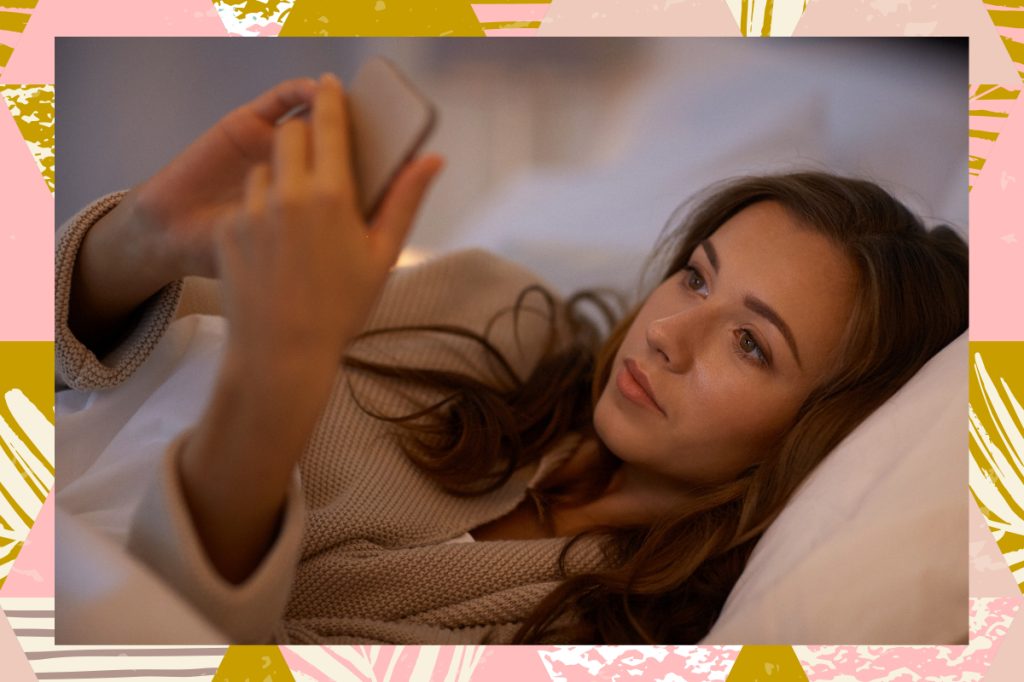 sad woman texting on phone from bed